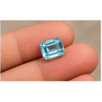 Aquamarine gemstone held on fingertips