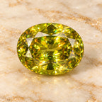 Sphene gemstone centered on warm marble